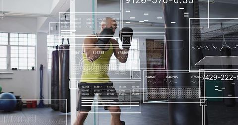 Boxer punching heavy bag with digital hud overlays in bright gym for training tech