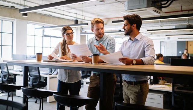 Young professionals collaborating at standing desk in modern bright open-plan workspace