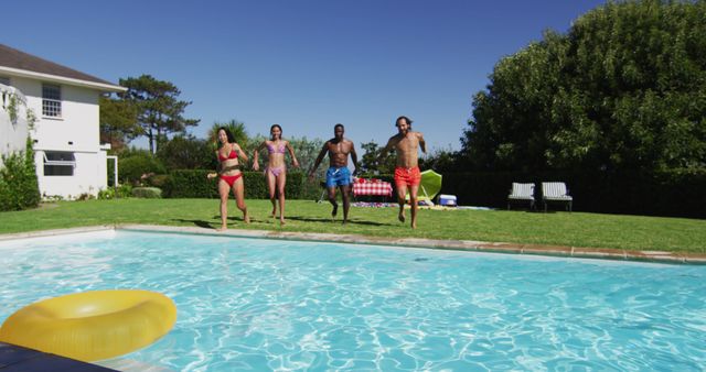 Diverse group of friends having jumping into a swimming pool. hanging out and relaxing outdoors in summer.
