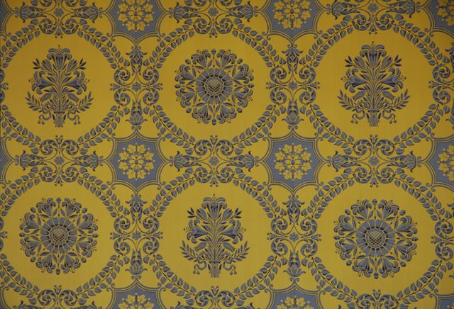 Elegant yellow and black wallpaper features ornate floral designs and intricate patterns ideal for adding vintage charm to homes or historical settings. Great for background usages in advertising, design projects, and bloggers focusing on retro or interior decor themes.