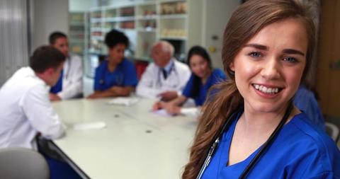 Smiling Nurse in Hospital Meeting with Medical Team in Background - Download Free Stock Images Pikwizard.com