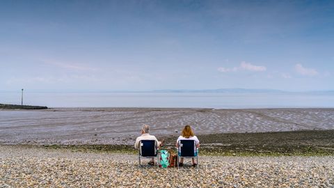 Couple Relaxing on Stony Beach Overlooking Calm Sea