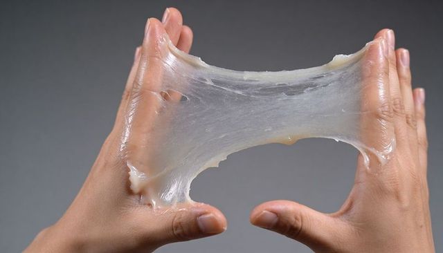 Closeup hands stretching translucent sticky film showing elasticity and glossy sheen