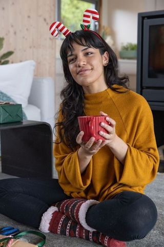 Festive Woman with Red Mug Celebrating Cozy Holiday at Home