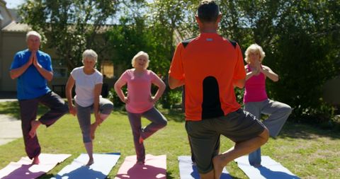 Senior Group Yoga Class Led by Personal Instructor in Garden