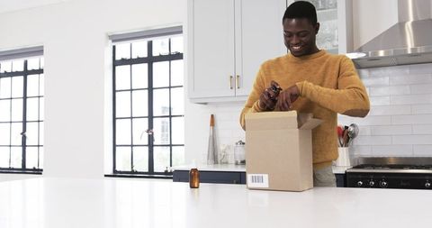 Man unpacking amber bottle at home kitchen island