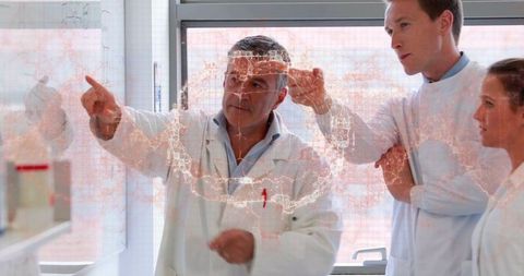 Lead scientist pointing at illuminated network map on glass while guiding research team
