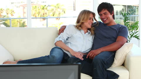 Joyful Couple Relaxing Together on Sofa Watching TV