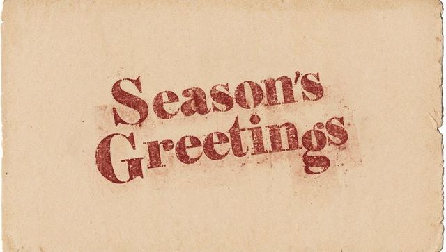 Vintage distressed 'season's greetings' stamp on aged beige paper with deckled edges
