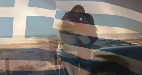 Romantic couple embracing on greek beach at sunset with flag overlay