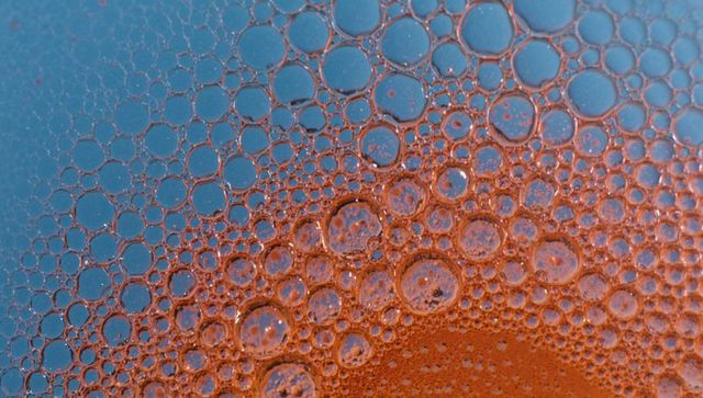 Macro bubble cluster blending warm orange and cool blue abstract liquid texture
