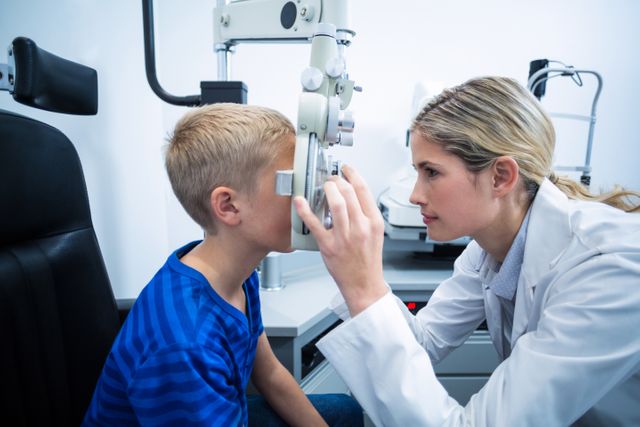 Female optometrist examining young patient on phoropter in ophthalmology clinic