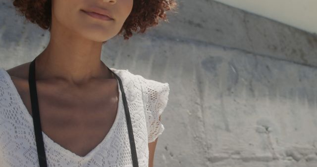 This image shows a confident young woman with curly hair, shared in close-up wearing a stylish white lace top. It captures a relaxed and fashionable street style look. Great for lifestyle, fashion, youth, and women's empowerment contexts.