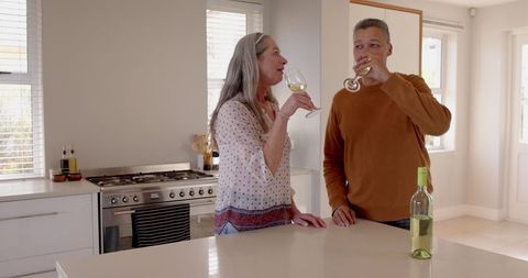 Senior Couple Toasting with Wine in Bright Modern Kitchen