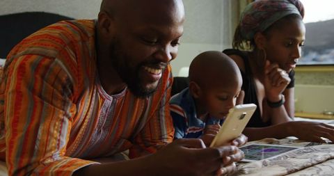 African american family connecting with multimedia devices on bed