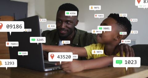 Father and son engaged with social media icons on laptop