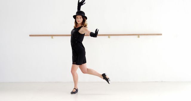 Young woman in black dress and hat performing ballet in a dance studio. Ideal for advertisements related to performing arts, dance lessons, elegant fashion, and creative movement.