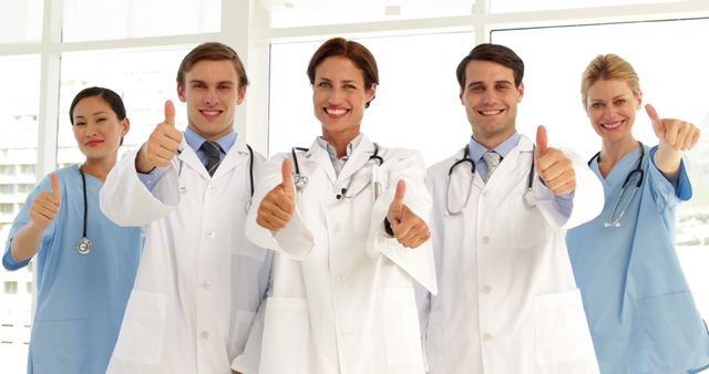 Confident medical team looking at camera and giving thumbs up at the hospital