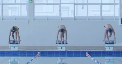 Three Male Swimmers Preparing on Starting Blocks in Competition Pool