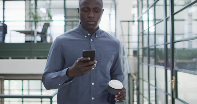 Young Professional Checking Smartphone While Holding Coffee in Modern Office - Download Free Stock Images Pikwizard.com