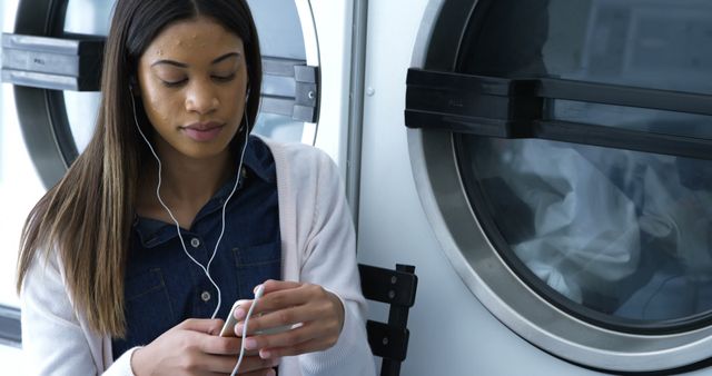 Young Woman Listening to Music in Laundromat - Download Free Stock Images Pikwizard.com