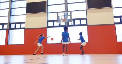 Diverse Female Youth Playing Basketball Indoors on Court