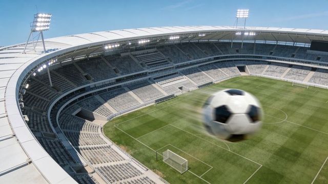 Close-up high-speed soccer ball streaking toward camera over empty modern stadium