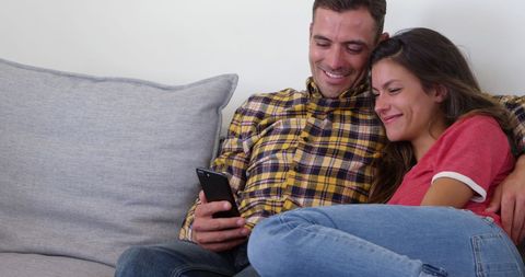 Couple Relaxing on Couch Smiling at Smartphone - Download Free Stock Images Pikwizard.com