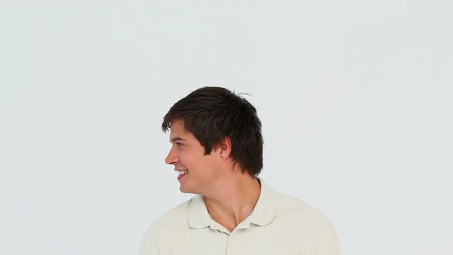 A young man is turning his head and smiling against a plain white background. His casual demeanor and laugh create a friendly and approachable atmosphere. Suitable for corporate presentations, advertising campaigns, or educational materials that convey warmth and positivity.