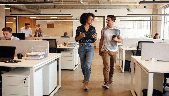 Colleagues walking and talking through modern open-plan office, casual collaboration