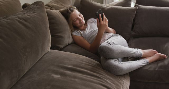 Relaxed Girl Enjoying Smartphone on Comfortable Couch at Home - Download Free Stock Images Pikwizard.com