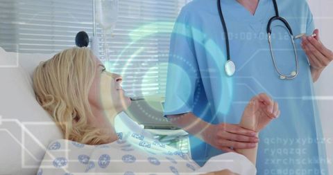 Patient reclining on hospital bed with clinician holding wrist and digital health interface