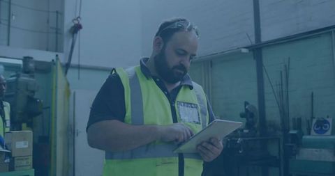 Technician Inspecting Tablet in Industrial Workshop