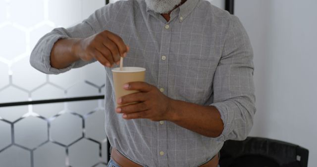 Person stirring coffee in paper cup at modern office - Download Free Stock Images Pikwizard.com