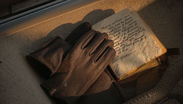 Sunlight casting on vintage leather gloves and cursive journal in car interior