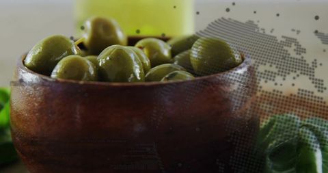 Organic green olives in rustic wooden bowl with dot map overlay