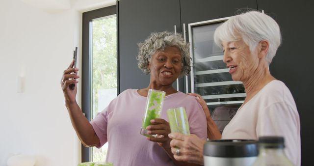 Elderly friends enjoying time together preparing green smoothies in a bright modern kitchen. Perfect for illustrating active senior lifestyles, healthy nutrition choices, social interactions during retirement, and promoting well-being among older adults.