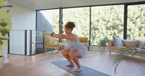 African American Woman Doing Yoga Squat in Modern Living Room