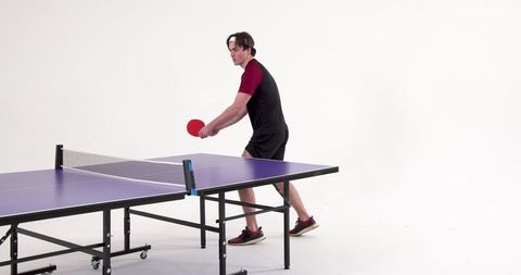 Man playing ping pong on purple table tennis table