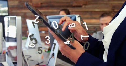 Businesswoman using tablet with floating numbers for data analysis in modern office team