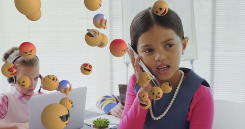 Children Engaging with Technology Surrounded by Floating Emoji Icons