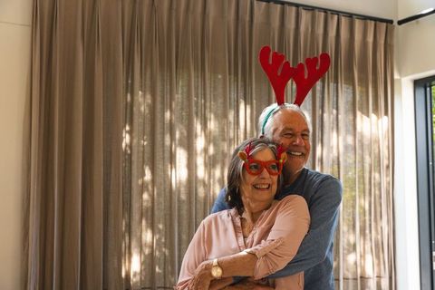 Senior Couple Embracing with Festive Holiday Antler Accessories