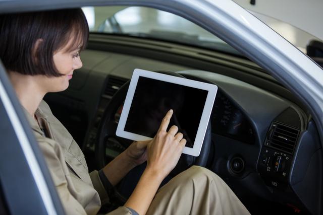 Female mechanic using digital tablet in car at a repair garage