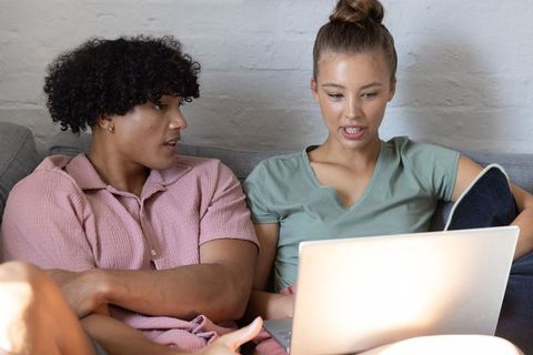Young couple collaborating on laptop while relaxing on couch for planning and remote work