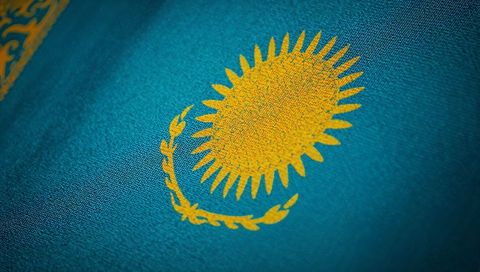 Kazakhstan Flag Close-Up Showing Golden Sun Emblem with Ornamental Stripe on Teal Fabric