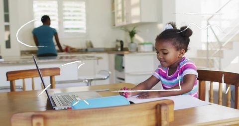 Young Girl Drawing at Kitchen Table with Laptop