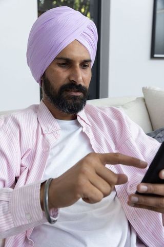 Man Wearing Turban Engaging with Smartphone at Home