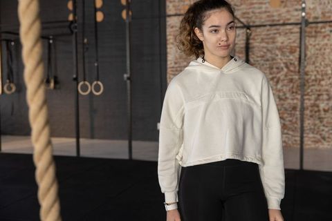 Woman standing in industrial gym wearing cropped hoodie and leggings