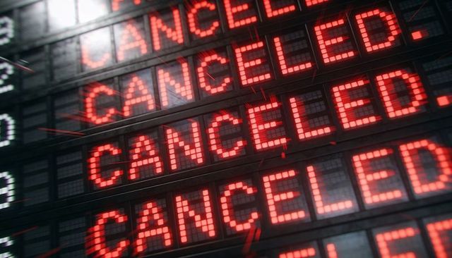 Canceled alerts on digital departure board, red led display showing travel disruption