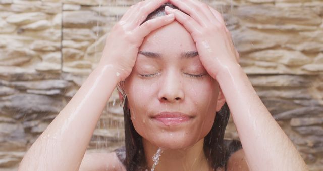 A young woman is enjoying a refreshing shower. This image can be used in advertisements for personal care products, wellness blogs, spa promotions, hygiene tutorials, and skincare brand campaigns.